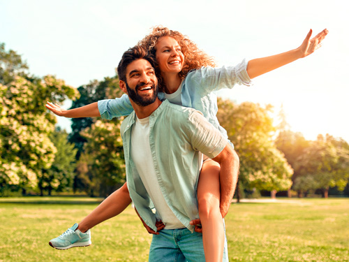 casal sorrindo em área livre com árvores
