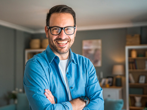 homem de pé com braços cruzados e sorrindo