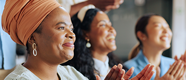 Pessoas sentadas em um ambiente interno aplaudindo.