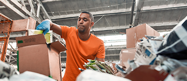 Pessoa organizando materiais recicláveis em um centro de triagem industrial.